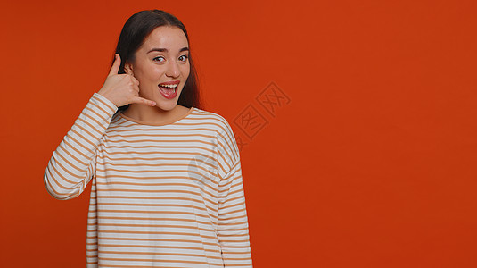 年轻一个看相机的女人 做电话手势 就像说嘿嘿 你给我打电话 回话电讯会议女孩黑发潮人网上购物成人红色广告服务图片