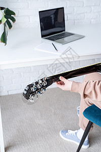 年轻女子在家弹吉他时学习在家里弹吉他艺术家爱好女性吉他手歌曲快乐青少年笔记本音乐音乐家图片
