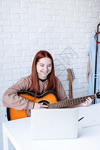 年轻女子在家弹吉他时学习在家里弹吉他幸福快乐爱好乐器笔记本房间吉他手女孩闲暇歌曲图片