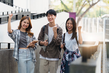 有朋友的美丽的年轻亚裔女大学生在户外 在大学校园工作的大学生背包休闲装快乐图书馆男性学校阅读技术青年微笑图片