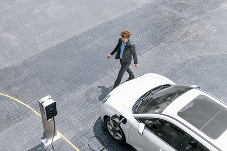 有EV汽车充电电池的进化商务人士的空中观察车站收费车辆商务插头城市发动机男人电动车力量图片