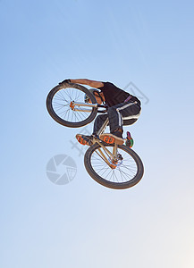 山地自行车 速度和运动 一名男子在户外从下方对着天空的比赛中在空中跳跃 蓝天 能量和自行车 有职业男性骑自行车的人或运动员在行动图片