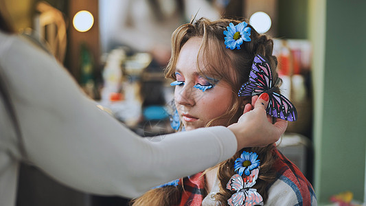 理发师用蓝花和蝴蝶来装饰模特的头发化妆品花圈女孩冒充青年成人理发护理女士女性图片