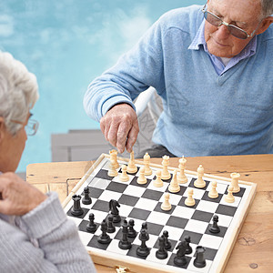用引人入胜的国际象棋游戏打发时间 一对老年夫妇正在下棋图片