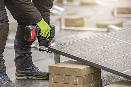 太阳能电池板安装人员使用铝制紧固件和无绳电钻将模块拧在一起 屋顶安装工作和安全 带复制空间的概念活力力量生态钻头房子蓝色技术工人图片