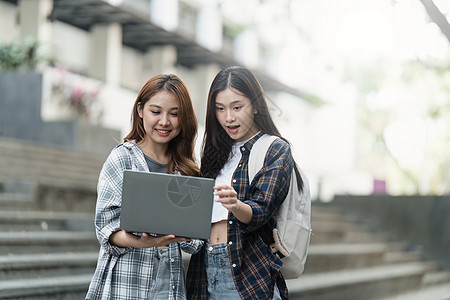 有朋友的美丽的年轻亚裔女大学生在户外 在大学校园工作的大学生电脑快乐背包班级团体青少年朋友们阅读女性男性图片