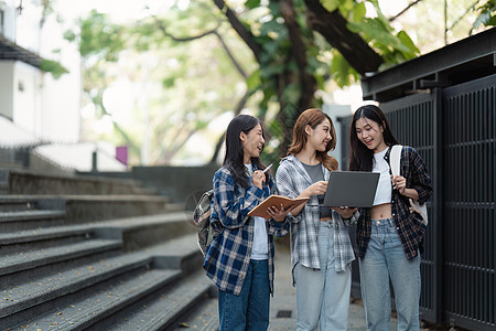 有朋友的美丽的年轻亚裔女大学生在户外 在大学校园工作的大学生青年休闲装学习背包快乐教育女性电脑微笑男性图片