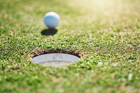 白天在高尔夫球场外的洞口边缘拍到高尔夫球的近距离镜头图片
