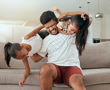 抱着妈妈的孩子快乐的父亲和女孩在家庭客厅的沙发上微笑着度过愉快的家庭时光 孩子们玩耍 爸爸和孩子们在黑人家庭的休息室沙发上玩耍 他们的幸福背景