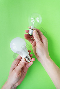 LED和白月灯是两类灯具 放在一个女孩的手中 她被隔离在绿色背景上 节能灯图片