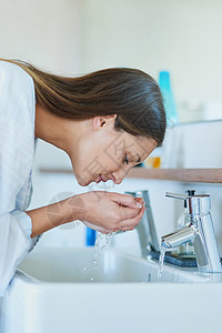 女性洗脸泼水年轻女子在家里浴室水槽上洗脸 她的脸被洗得一干二净的背景