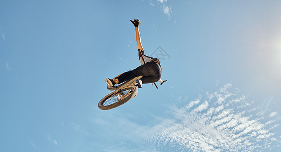 自行车特技 男子骑自行车在蓝天的空中跳跃模拟运动表演 健身训练或户外自行车表演 有 bmx 自行车冒险模型的职业运动员图片