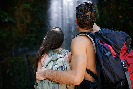 一对年轻情侣一起站在一起看着瀑布的后视镜镜头 简直太壮观了图片