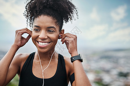 一位运动的年轻女子在户外锻炼时听音乐 我们来听听这个音乐吧图片