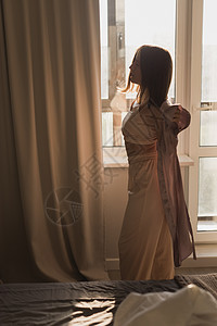 年轻妇女在卧室享受阳光明媚的早晨     觉醒和健康概念房间女性苏醒酒店窗帘活力太阳窗户晴天喜悦图片