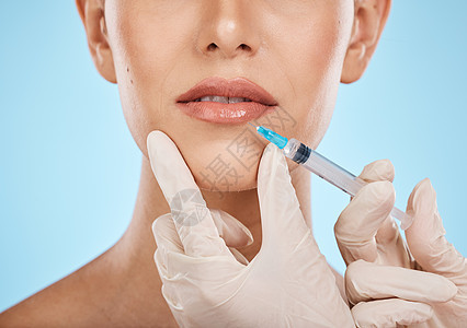 特写镜头 女人和嘴唇上的针 用于化妆品 皮肤病学和美容 健康治疗以及蓝色工作室背景 女性 女士和口腔注射 整形手术和护肤图片