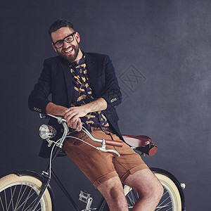 我的风格规则 一个时髦的年轻人 骑着自行车在工作室摆姿势的肖像图片