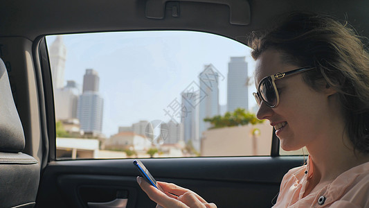 一个女孩在一辆移动的汽车里 正在打一个信息 在手机上 迪拜市图片
