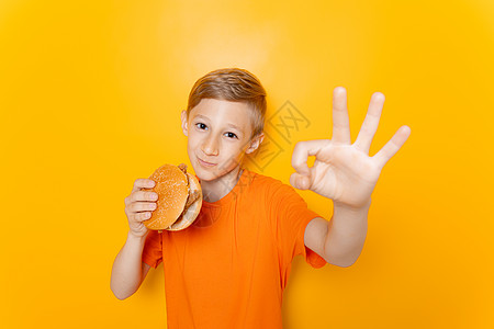 男孩吃汉堡包 在黄色背景上表现不错图片