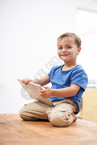 坐在地球上看书看着Dads触摸板 一个男孩坐在桌子上玩数字平板电脑的肖像背景