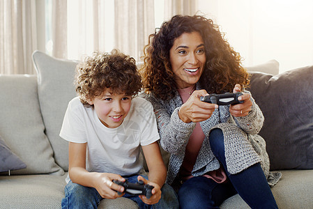 今天是我的小冠军的比赛日 一位年轻的母亲和她的儿子在家里一起玩电子游戏图片