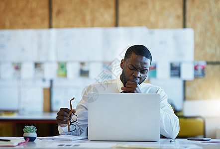 一名商务人士在办公室用笔记本电脑工作时打哈欠 这又是一个漫长的一天图片