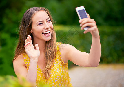 一个无忧无虑的年轻女人 在公园里用手机拍自拍 玩个游戏 她很爱听别人说话图片