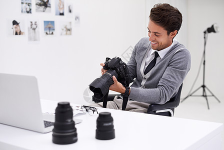 摄影师坐在办公室的桌子上拿着照相机 他用摄像头拍到一个摄影师的照片图片