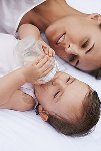 保持婴儿的健康 一个母亲在爱的看着她的婴儿喝瓶酒时女性成人青年微笑幸福孩子牛奶儿童父母童年图片