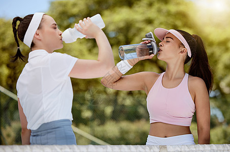 网球 健身和水 女性在炎热的夏日阳光下在球场上喝水 体育锻炼 健康友谊和训练锻炼 女朋友在比赛或比赛中喝水图片