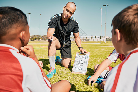 足球队 儿童和带剪贴板的教练在谈论锻炼计划 训练和战术时在户外足球场进行健身 比赛和运动 男子与足球队规划比赛交谈图片