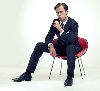 一位英俊年轻绅士的摄影棚肖像 穿着套式西装坐在椅子上图片