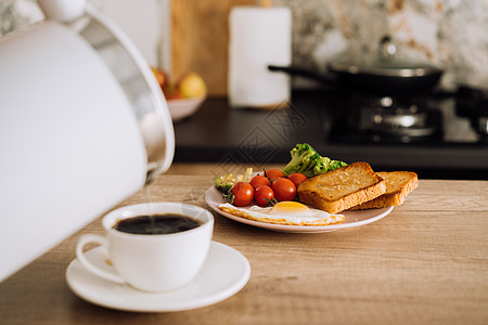 在厨房的木制桌上 自己做的早餐 模糊的咖啡杯和水壶放在前台图片