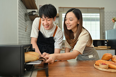 离婚夫妇在现代厨房一起准备晚饭 从烤箱中脱下法国面包面包包面包图片