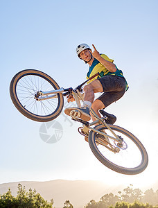 骑自行车 跳跃和摇滚 一名男子 bmx 骑手跳过自然界小径或路线上的坡道 天空 山地和骑自行车 一名男运动员在健身运动中在半空中图片