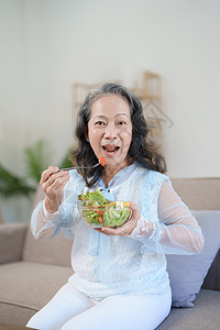 一位年长的亚洲妇女通过吃沙拉来照顾自己的健康食品沙发成人家庭老年午餐退休蔬菜夫妻女性图片