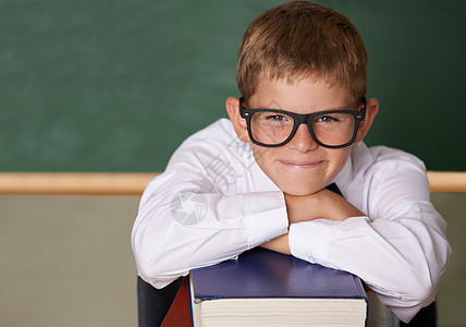 家庭作业没问题 一个快乐的年轻男生 戴着眼镜 系着领结 靠着一摞书对着镜头微笑图片