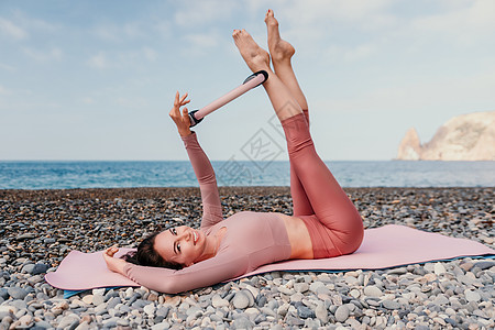 女人海普拉提 运动快乐的中年妇女在海边的海滩上练习健身 在户外瑜伽垫上微笑着进行积极的女性训练 享受健康的生活方式 和谐和冥想戒图片