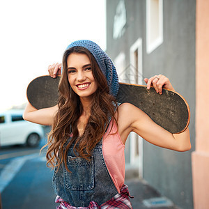 她拥有滑冰所需的一切 白天 一位迷人的年轻女滑手在她背后背着滑板的画像图片