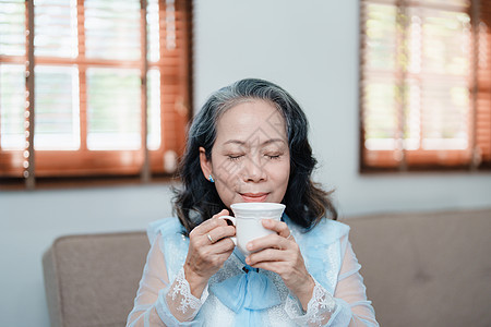 一位亚洲老年妇女为健康而喝茶的肖像沙发祖母厨房女性午餐微笑成人桌子家庭烹饪图片