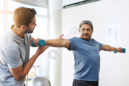 你做得很好 年轻的男性理疗师 在诊所帮助成熟的男性病人运动锻炼手术 他正在医院工作图片