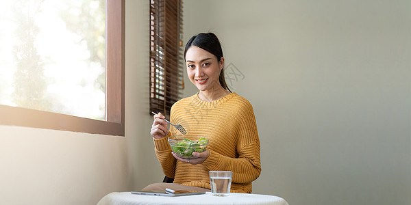 在家里为健康而吃食物的受优待妇女午餐绿色植物快乐饮食桌子女性厨房微笑蔬菜营养图片