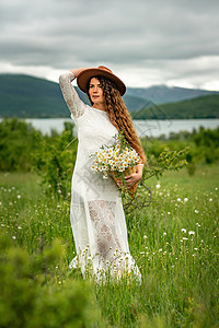 怀着白裙子和棕帽子的中年妇女手里握着一束盛大的花朵 祝贺之野花植物群雏菊乡村园艺季节草地荒野洋甘菊植物花瓣图片