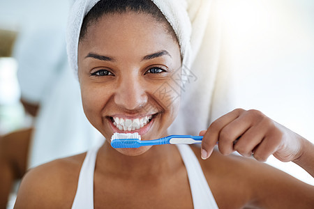 健康的牙齿是快乐的牙齿 一个年轻漂亮的女人在家里的浴室里刷牙的画像图片