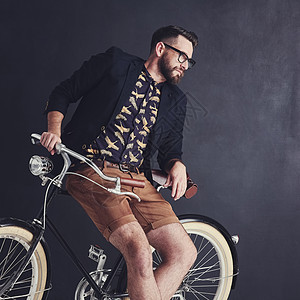 一个时髦的年轻人 骑着自行车在工作室里摆姿势图片