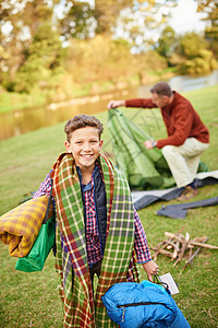 我准备好为这次露营之旅做任何事了 一个年轻男孩的肖像 带着露营装备和他父亲在背景中背景图片