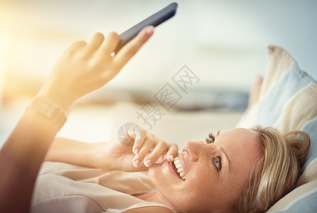 即时消息 即时幸福 一个成熟的女人在家里的沙发上放松时阅读短信图片
