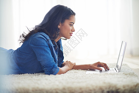 一位年轻女性在家里的笔记本电脑上浏览网络 在墙上的柱子上搜索背景图片