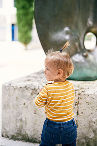 小女孩站在雕塑前 头转向侧面 向后看 近距离靠近一点图片