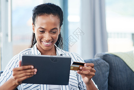 我要买下这个 一个年轻女人 在家里用信用卡和数字平板电脑做客图片